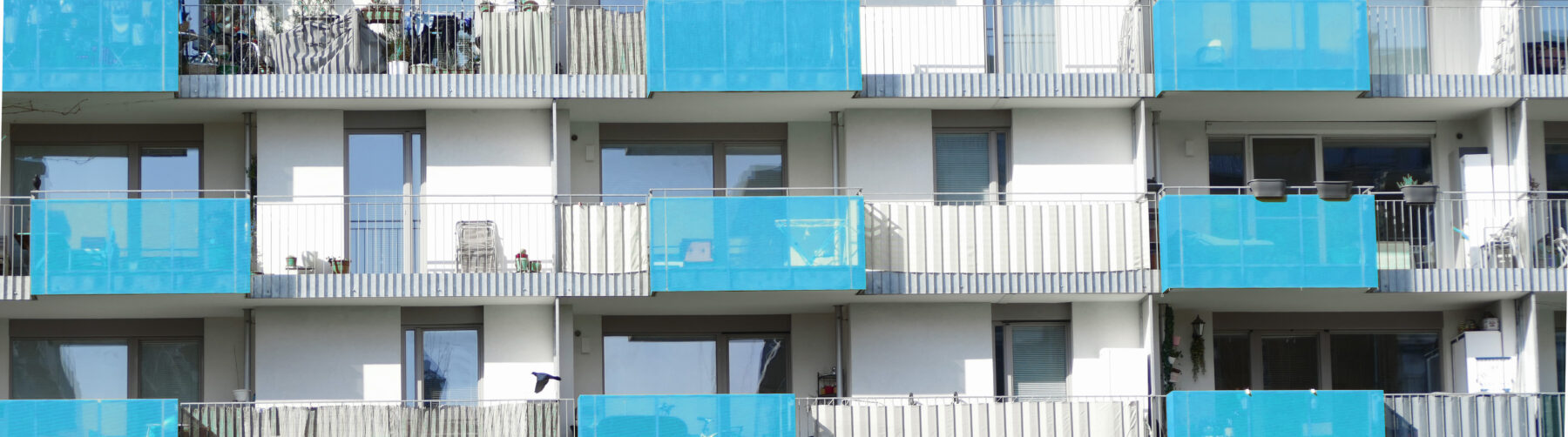 Weiße Häuserfassade mit blauen Balkonen